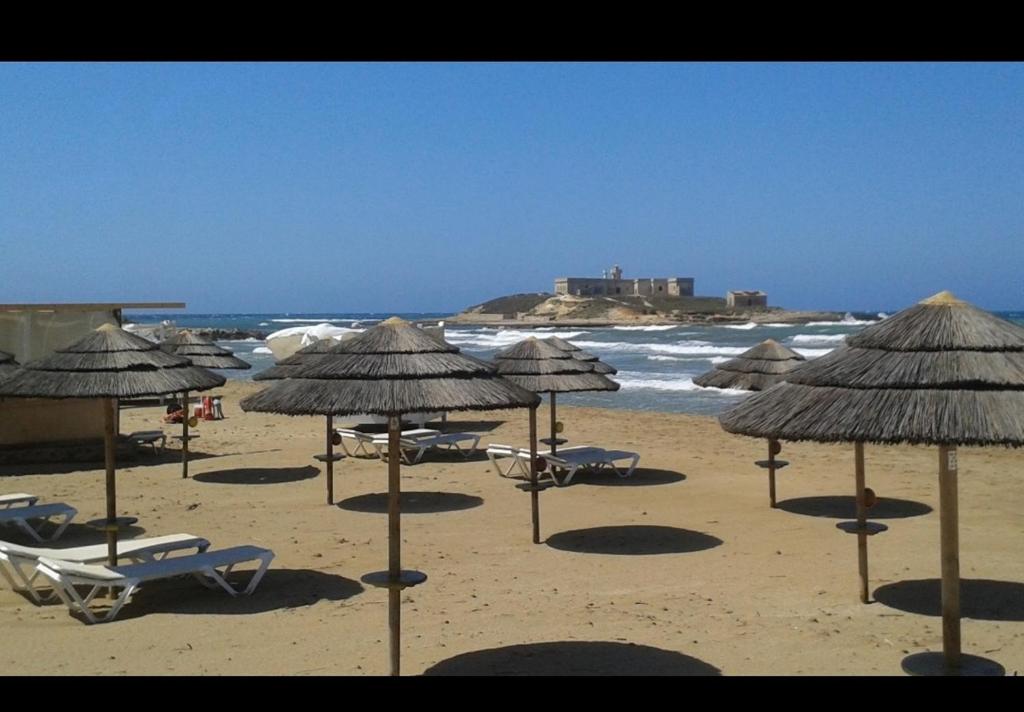 波爾托帕洛的住宿－Casa del sole，海滩上的一组椅子和遮阳伞