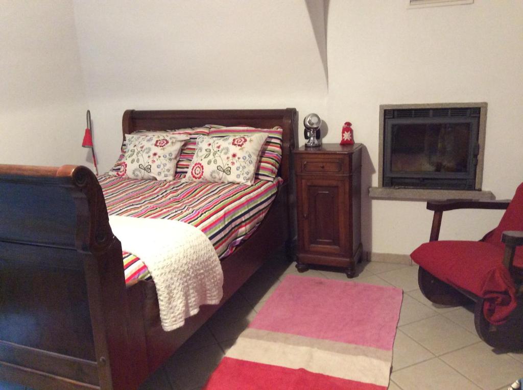 a bedroom with a bed and a chair and a fireplace at I "Giardin" in Crissolo