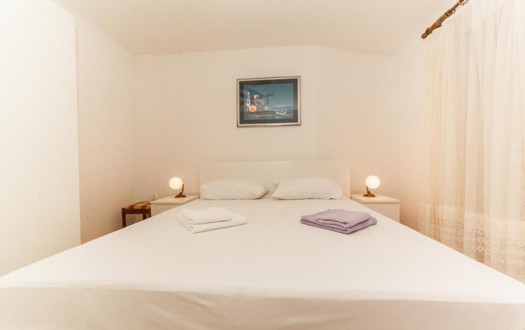 una camera da letto con un letto bianco con due asciugamani di Apartments Fedrigo a Sutivan (San Giovanni di Brazza)