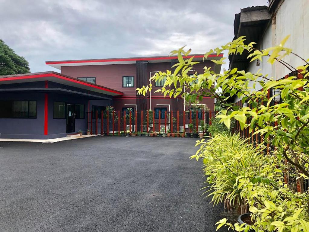 een rood gebouw met een hek ervoor bij Thyme Xeriscape Hostel in Kanchanaburi