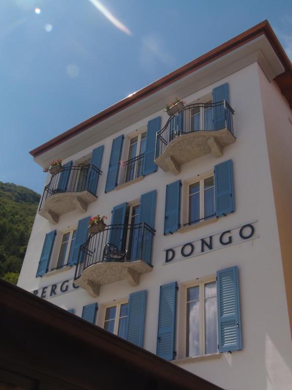 a white building with blue shutters and windows at Albergo Dongo in Dongo