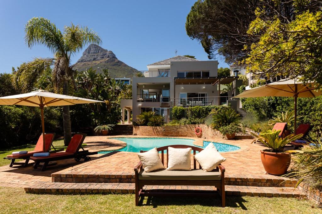 a house with a swimming pool and two chairs and umbrellas at 42 On Strathmore in Cape Town