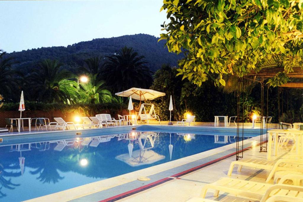 a swimming pool with chairs and umbrellas at night at Hotel Della Baia in Portovenere