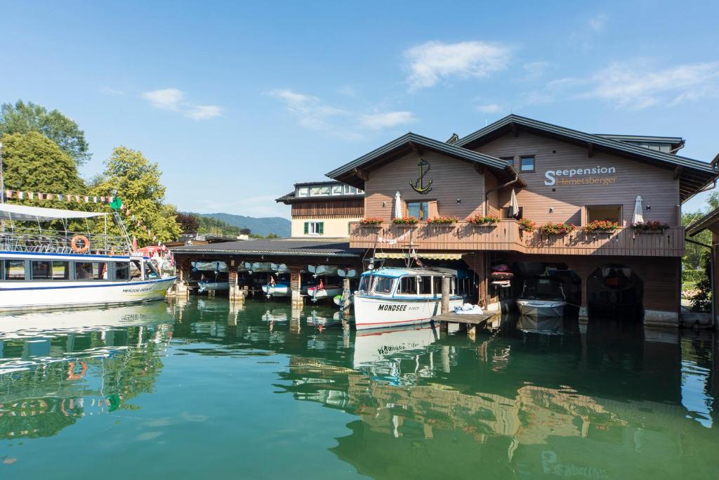 a building on a river with boats in the water at Seepension Hemetsberger in Mondsee