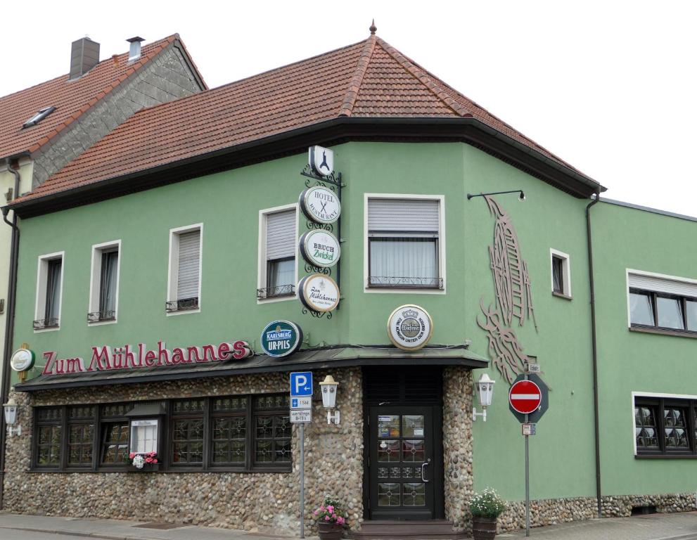 a green building with clocks on the front of it at Zum Mühlehannes in Rohrbach