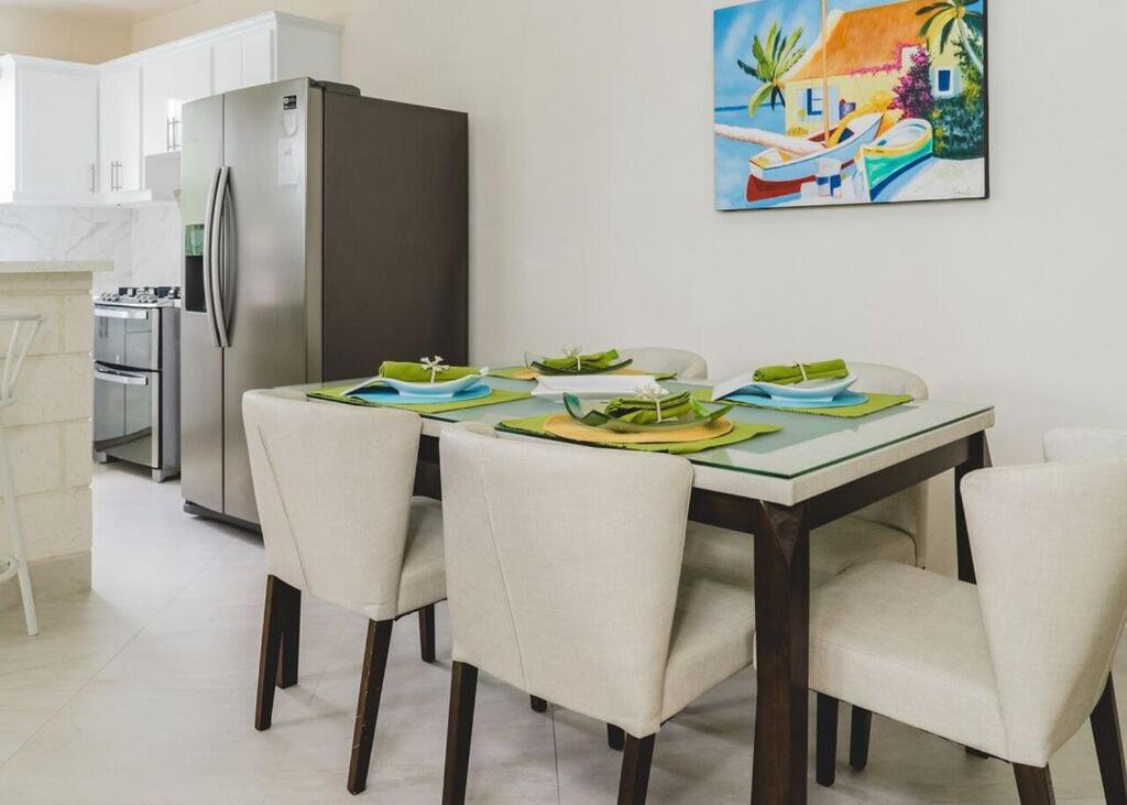 eine Küche mit einem Tisch mit Stühlen und einem Kühlschrank in der Unterkunft Ez Living Apartments in Bridgetown