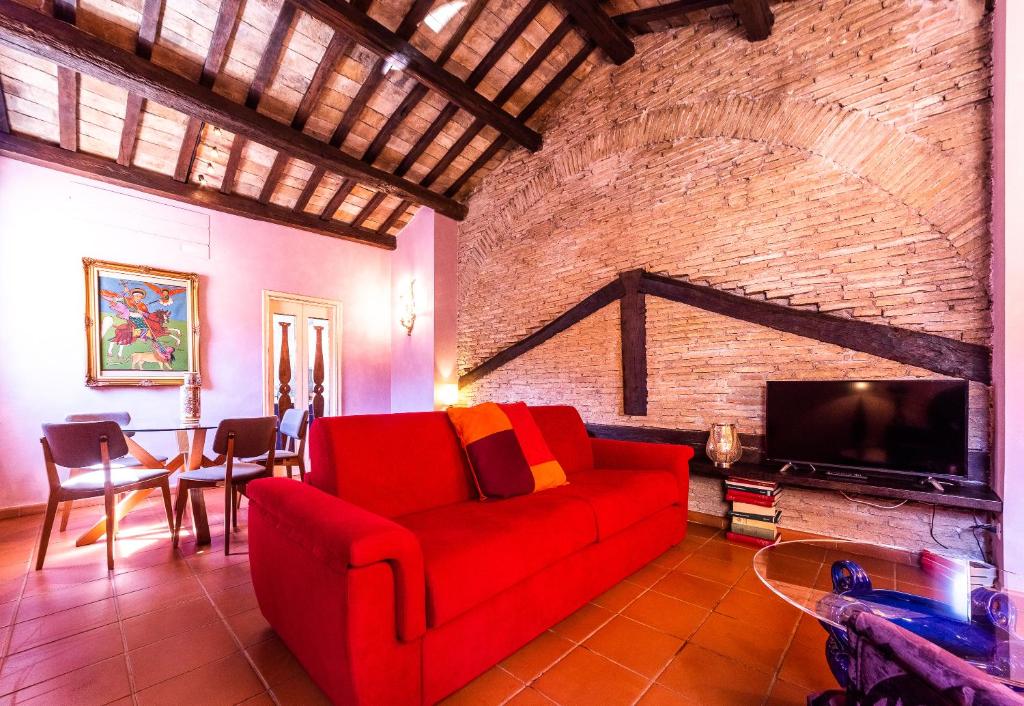 ein Wohnzimmer mit einem roten Sofa und einer Ziegelwand in der Unterkunft maison specchi in Rom