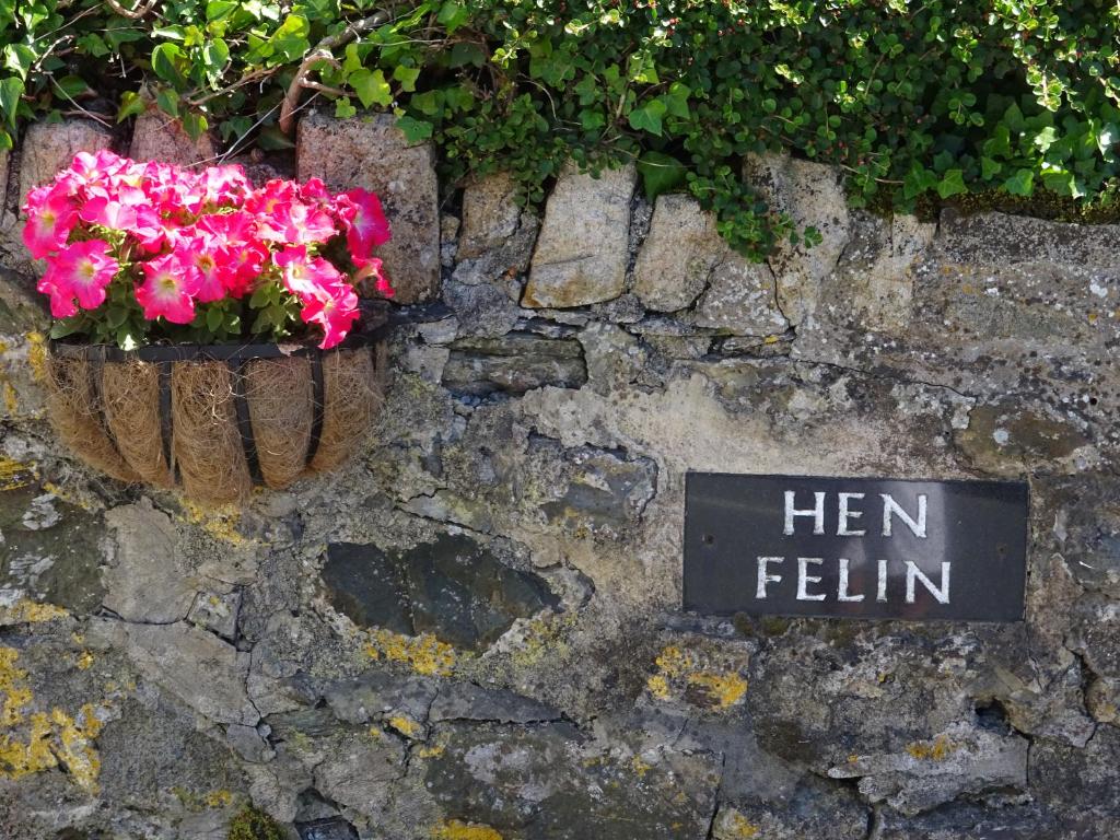 a sign on a stone wall with pink flowers at Yr Hen Felin - The Old Mill B&B in Morfa Nefyn