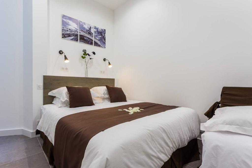 2 łóżka w pokoju z białymi ścianami w obiekcie Le Logis de Montmartre w Paryżu