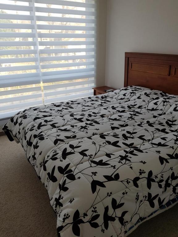 1 cama con edredón blanco y negro y ventana en Condominio Parque Payllahue, en Pucón