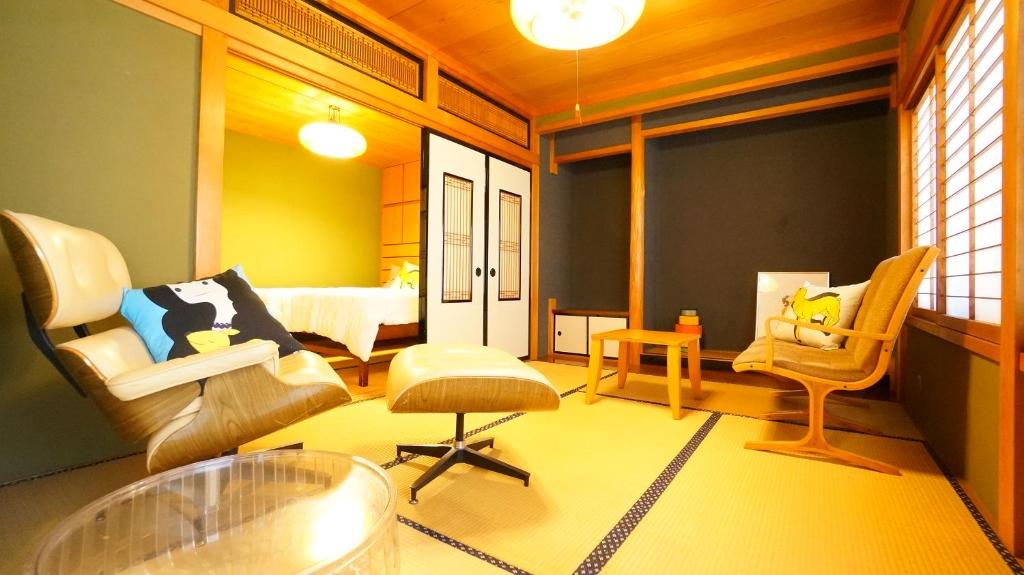 un soggiorno con 2 sedie e un letto di Tomato House Takayama a Takayama