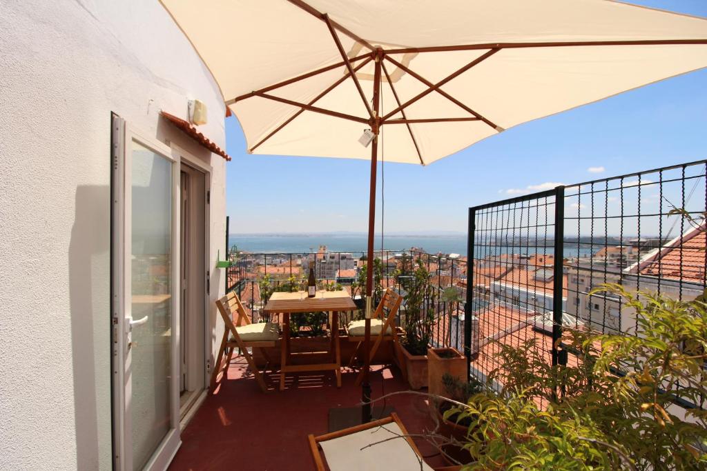 einen Balkon mit einem Tisch und einem Sonnenschirm in der Unterkunft Estrela Penthouse - Amazing Views in Lissabon