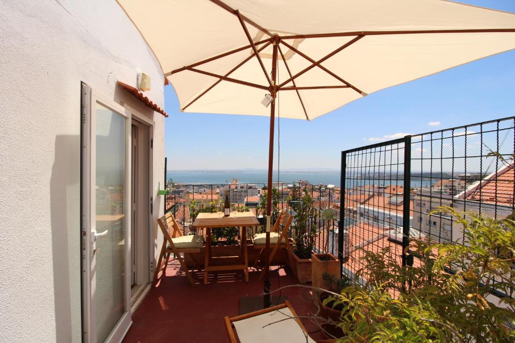 a balcony with a table and an umbrella at Estrela Penthouse - Amazing Views in Lisbon