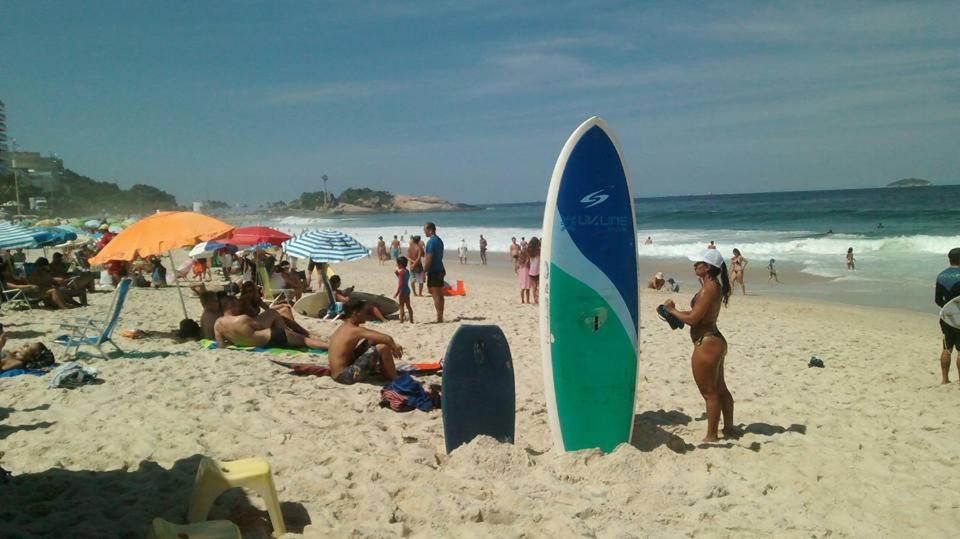 un grupo de personas en una playa con una tabla de surf en la arena en Kitinete Ipanema, en Río de Janeiro