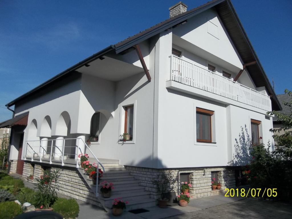 Biały dom ze schodami i balkonem w obiekcie Virágos Vendégház Balatonfüred w Balatonfüred