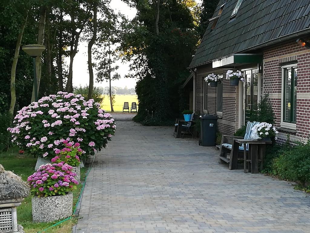 a brick walkway next to a building with flowers at Appartement De Molshoop in Landsmeer