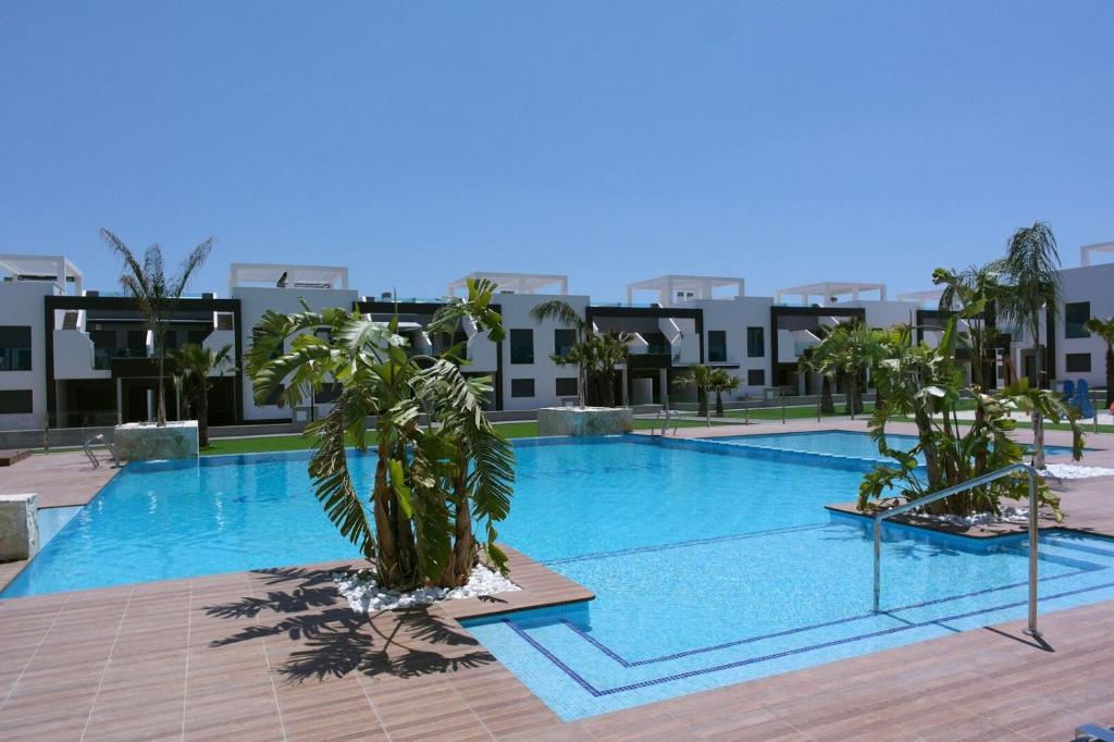 einem großen Pool mit Palmen vor einem Gebäude in der Unterkunft Oasis Beach X app 25 in Guardamar del Segura