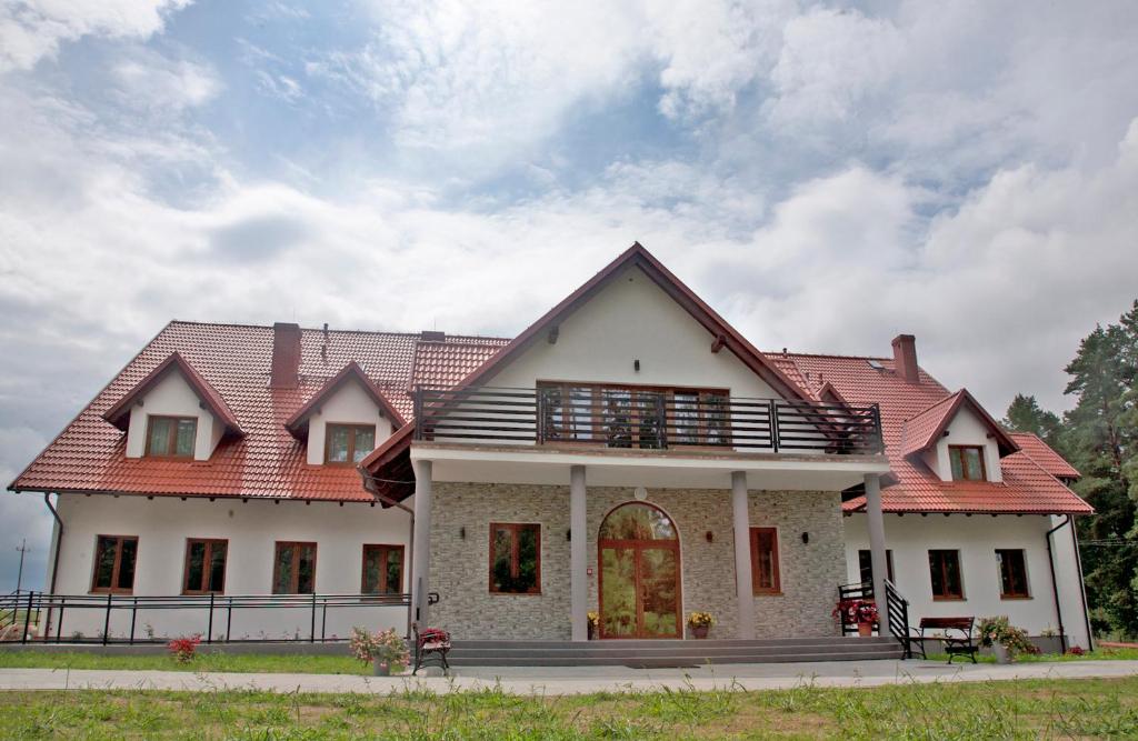 a large white house with a red roof at Mazurska Osada in Kleszczewo