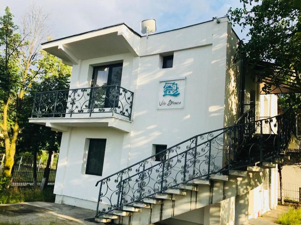 a white building with a balcony and a staircase at Vila Blanca in Alexandru cel Bun