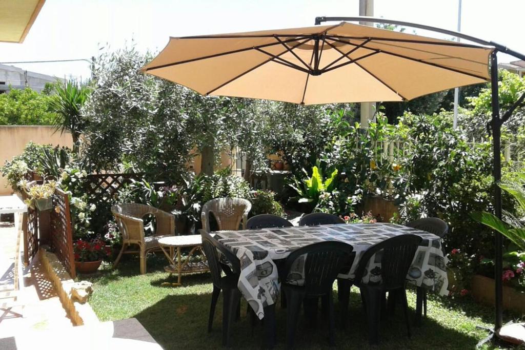 uma mesa e cadeiras debaixo de um guarda-sol num quintal em The Garden em Tortolì