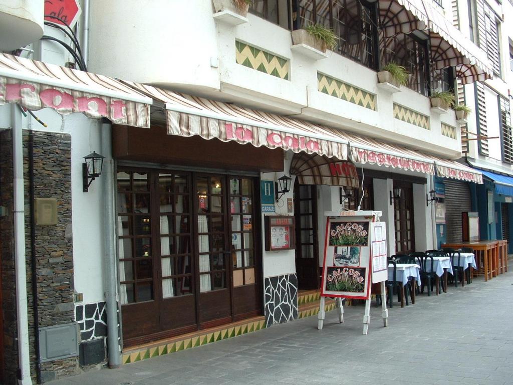 un restaurante con mesas y un cartel delante en Hotel La Cala en Rosas