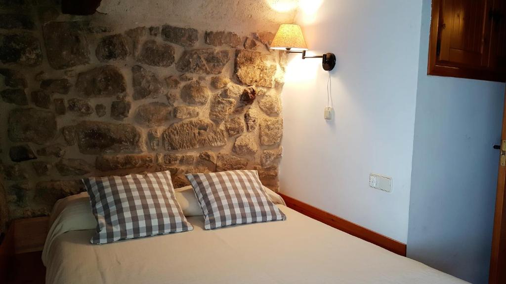 1 cama con 2 almohadas en una habitación con pared de piedra en Casa Templers, en Horta de Sant Joan