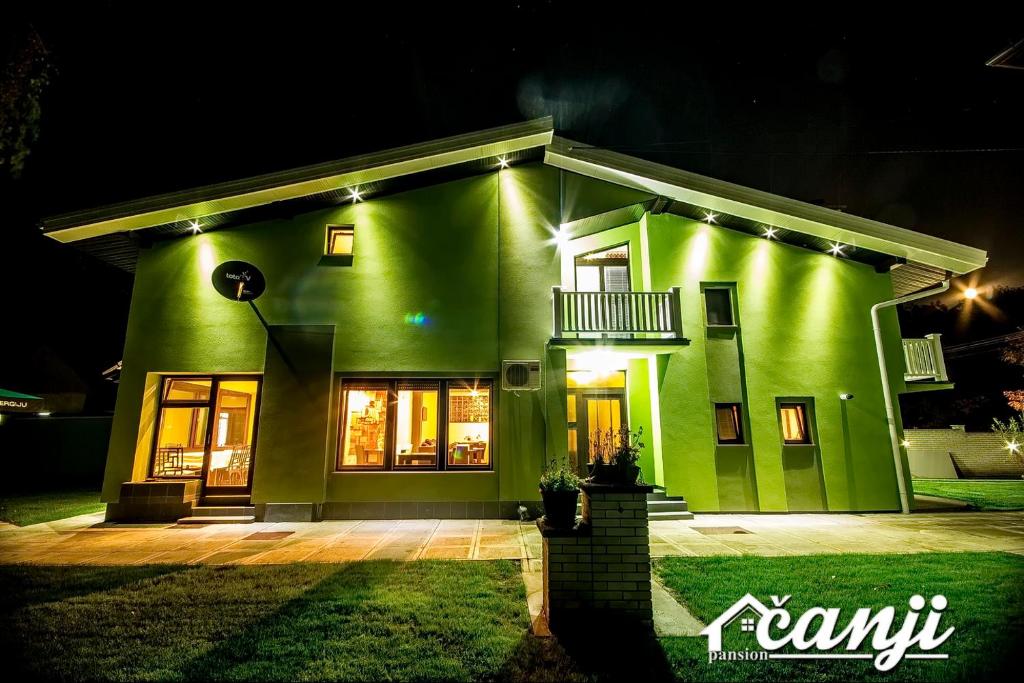 a green house with lights on it at night at Pansion Čanji in Bački Petrovac