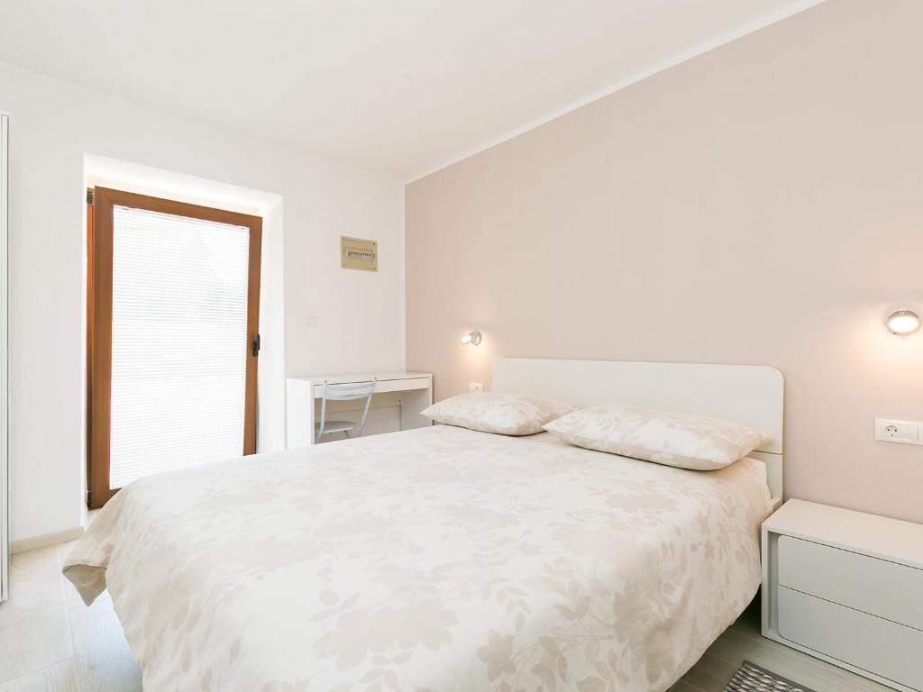 um quarto branco com uma cama branca e uma janela em Ninas em Visnjan