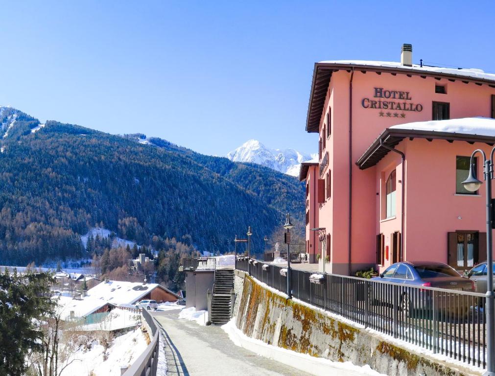 una cittadina in montagna con un edificio rosa di Hotel Garni Cristallo a Ponte di Legno