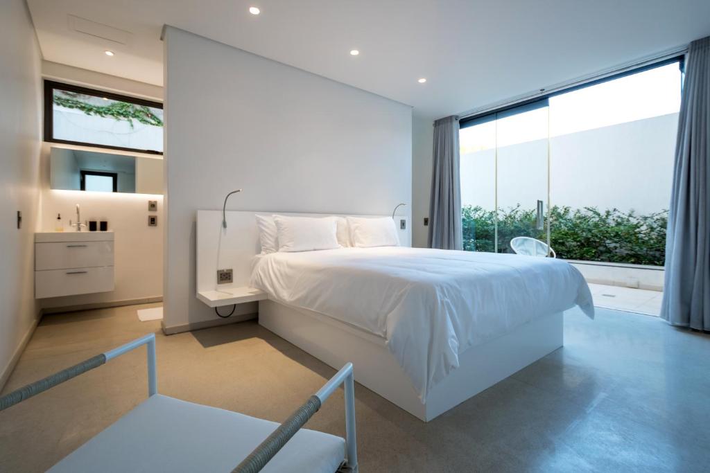 a bedroom with a white bed and a large window at Livega House in Windhoek