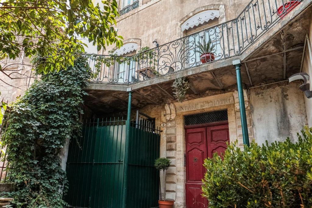 una puerta roja en un edificio con balcón en Les suites de Peyrat en Pézenas