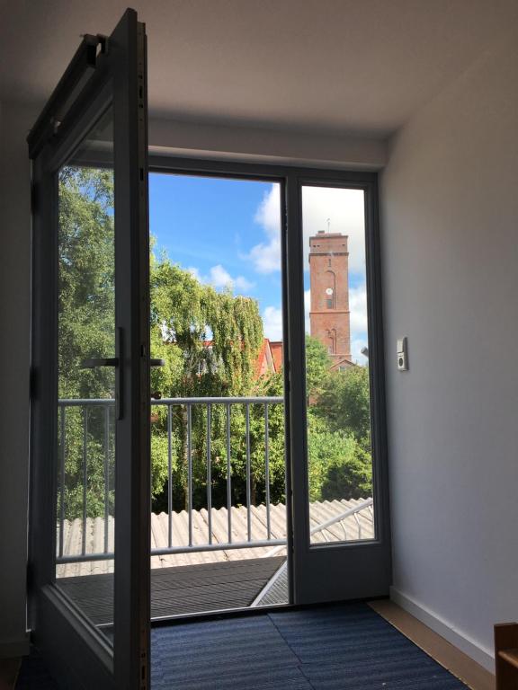 an open door to a balcony with a clock tower at Altes Zollhaus in Borkum
