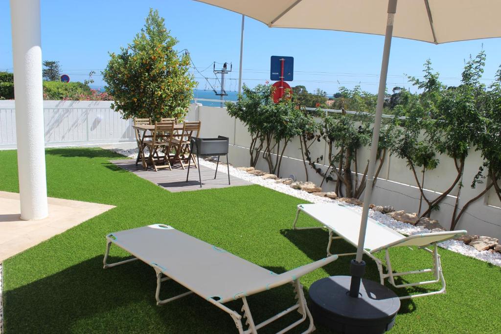 a patio with two chairs and an umbrella on the grass at Encosta´s Garden in Oeiras