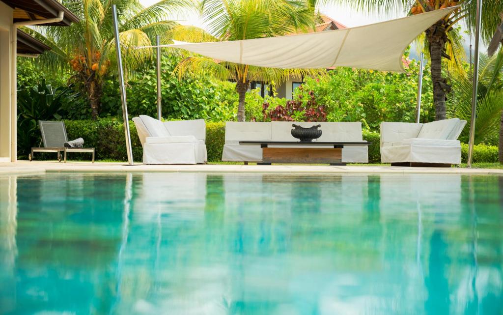 - une piscine avec des chaises, une table et un parasol dans l'établissement Eden Island Luxury Villa 235 by White Dolphin LLC, à Eden Island