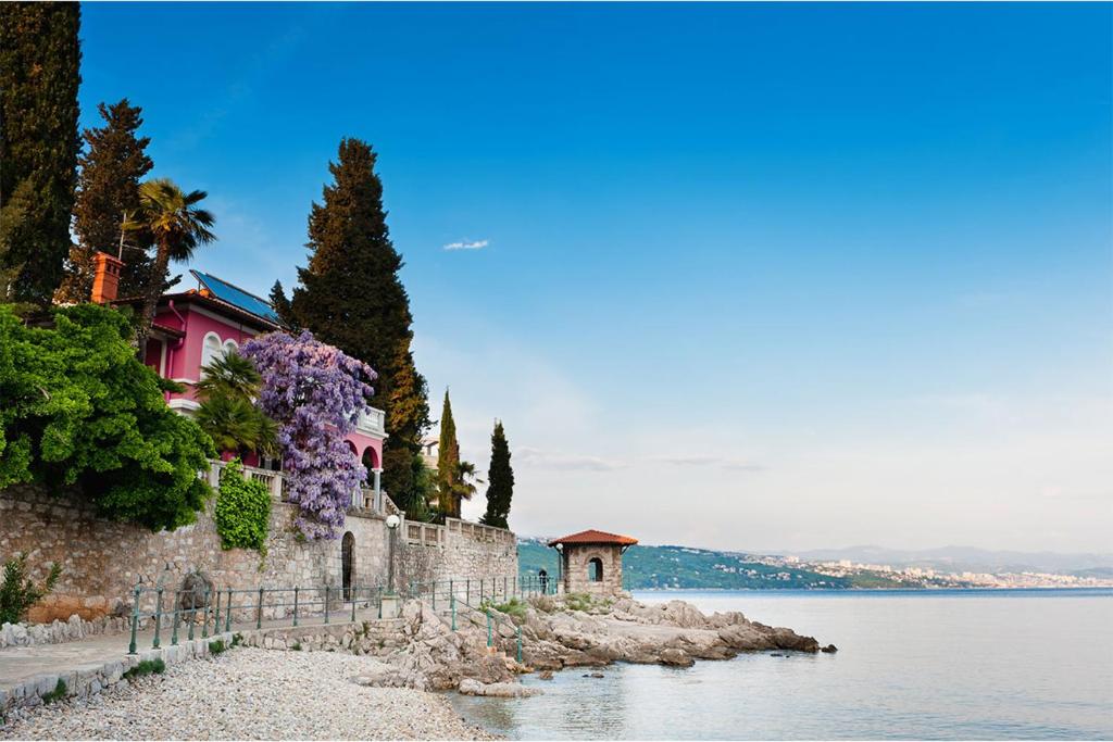 a house with purple flowers next to the water at The routes of Habsburg (beach 70 m) in Opatija