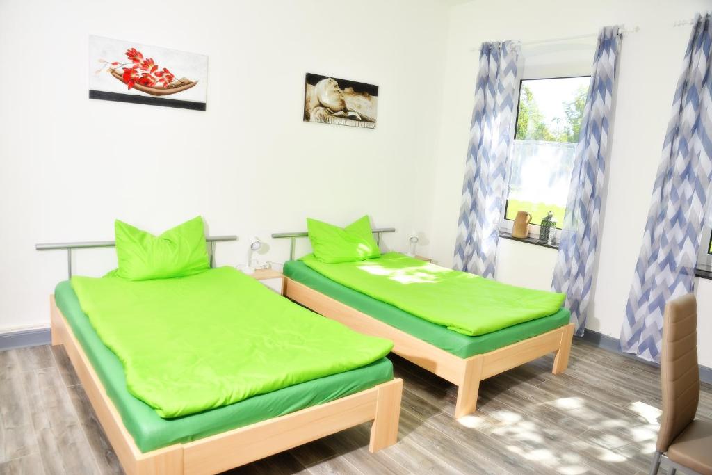 two beds in a room with green sheets at Lüggerts in Ennigerloh