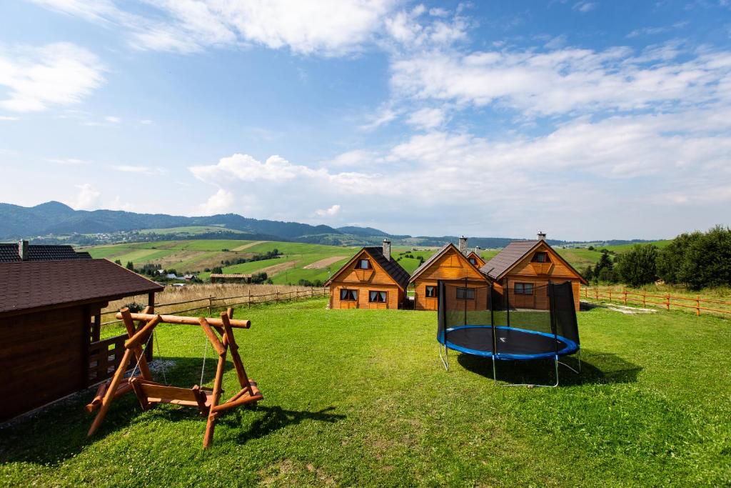 einen Hof mit einem Spielplatz mit Holzhäusern in der Unterkunft Domki u Bronki in Grywałd