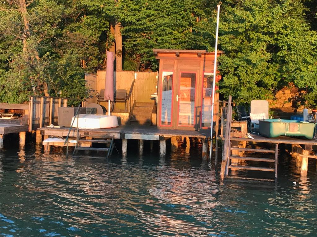 a dock with a small house and a boat on the water at Appartment in Kammerl in Schörfling