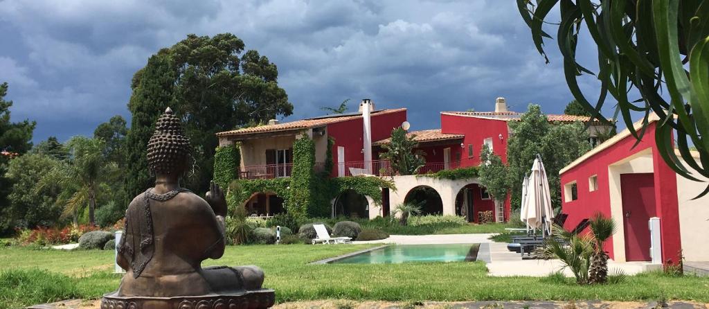 a red house with a statue in front of it at VILLA MERCEDES 300 m de la plage in La Londe-les-Maures