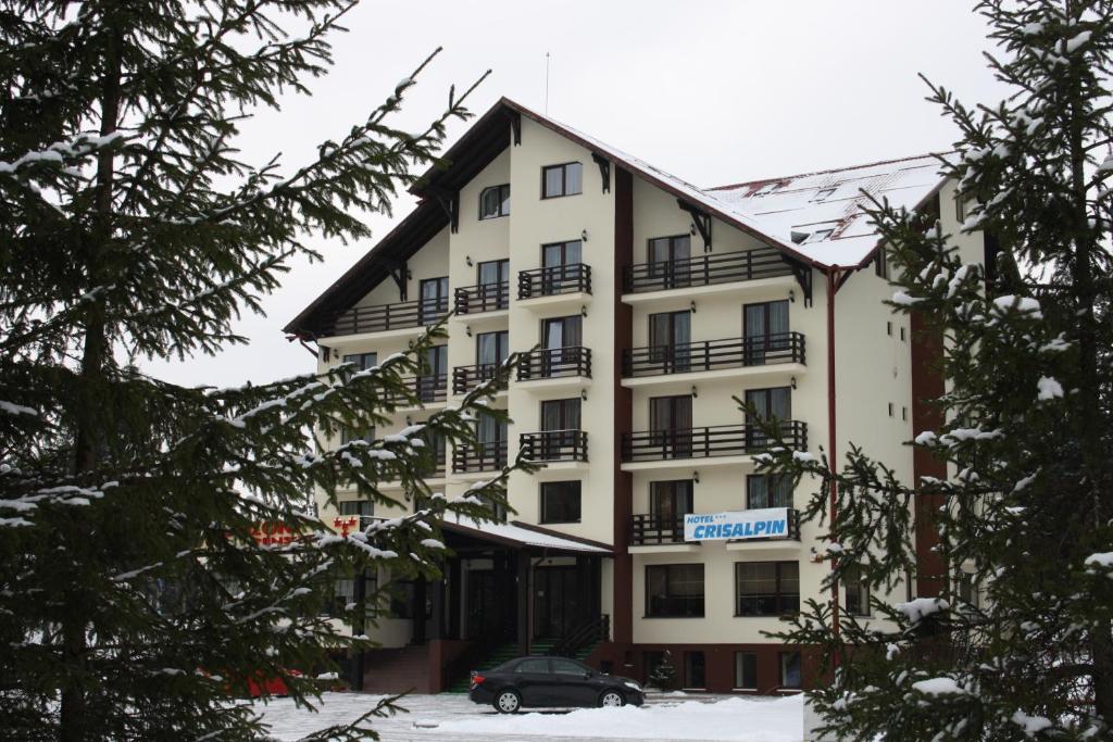 un edificio con un coche aparcado delante de él en Hotel Crisalpin en Poiana Brasov