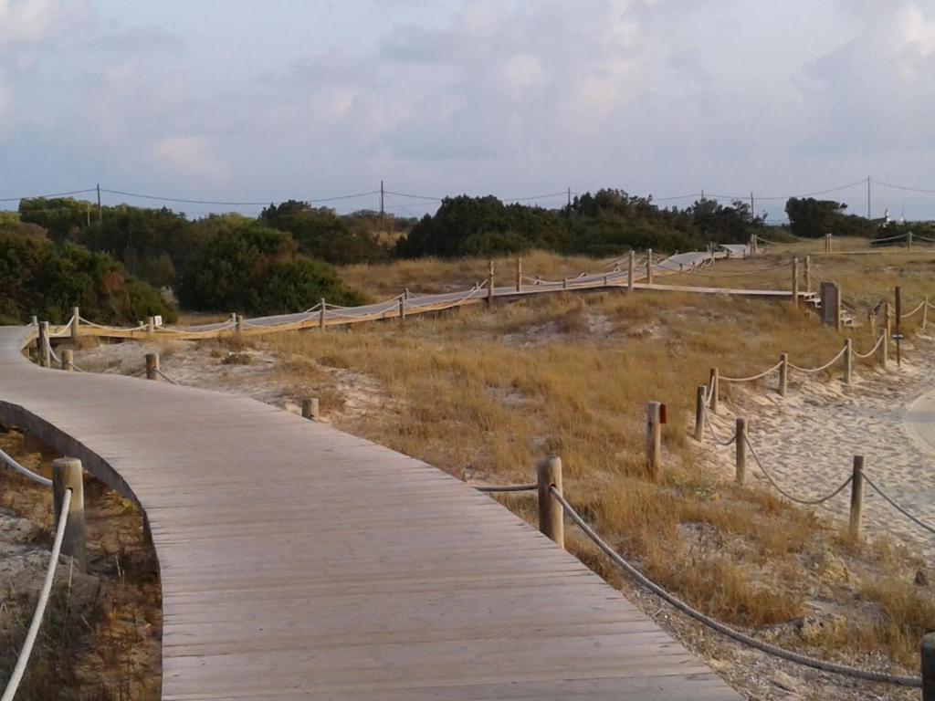 a wooden boardwalk on the side of a beach at Hotel Roca Bella in Es Pujols