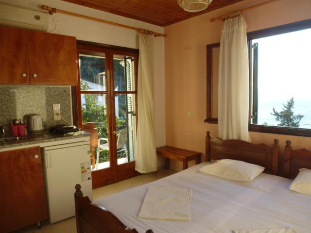 a bedroom with a bed and a kitchen with a window at Studios Andreas in Boukari