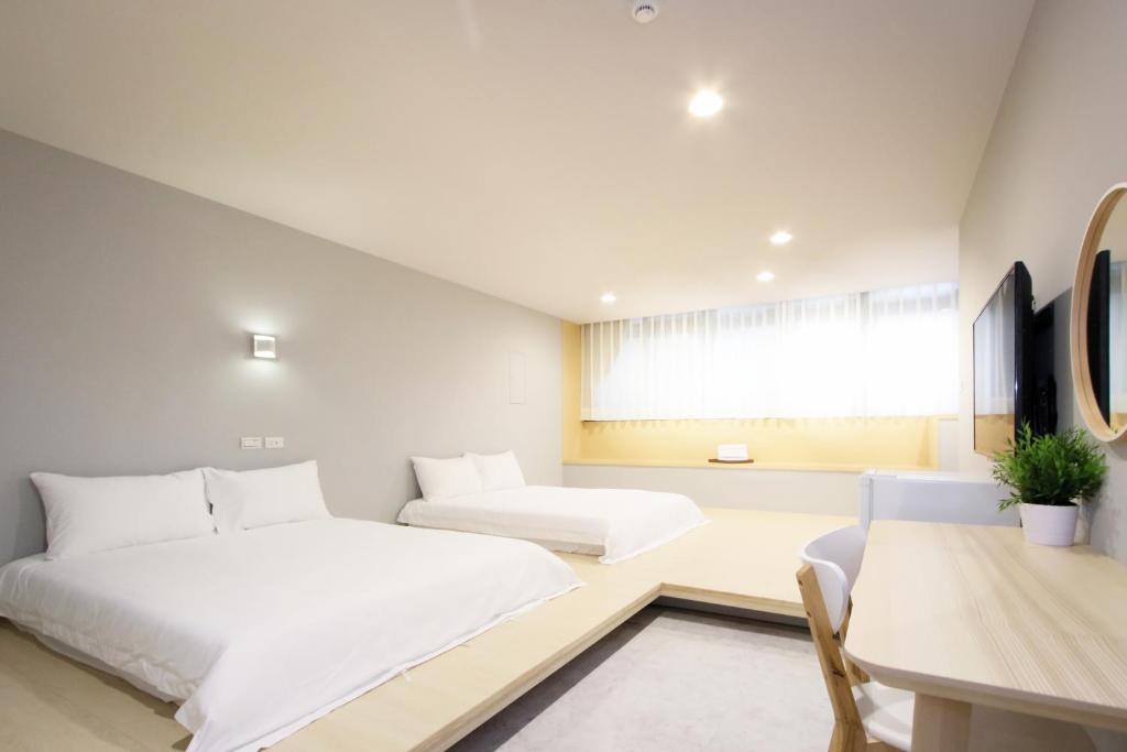 a bedroom with two beds and a table and a desk at Place Inn Taipei in Taipei