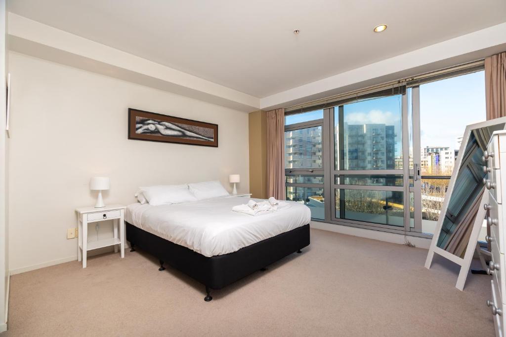 a bedroom with a bed and a large window at Wonderful Apartment Hobson Gardens in Auckland