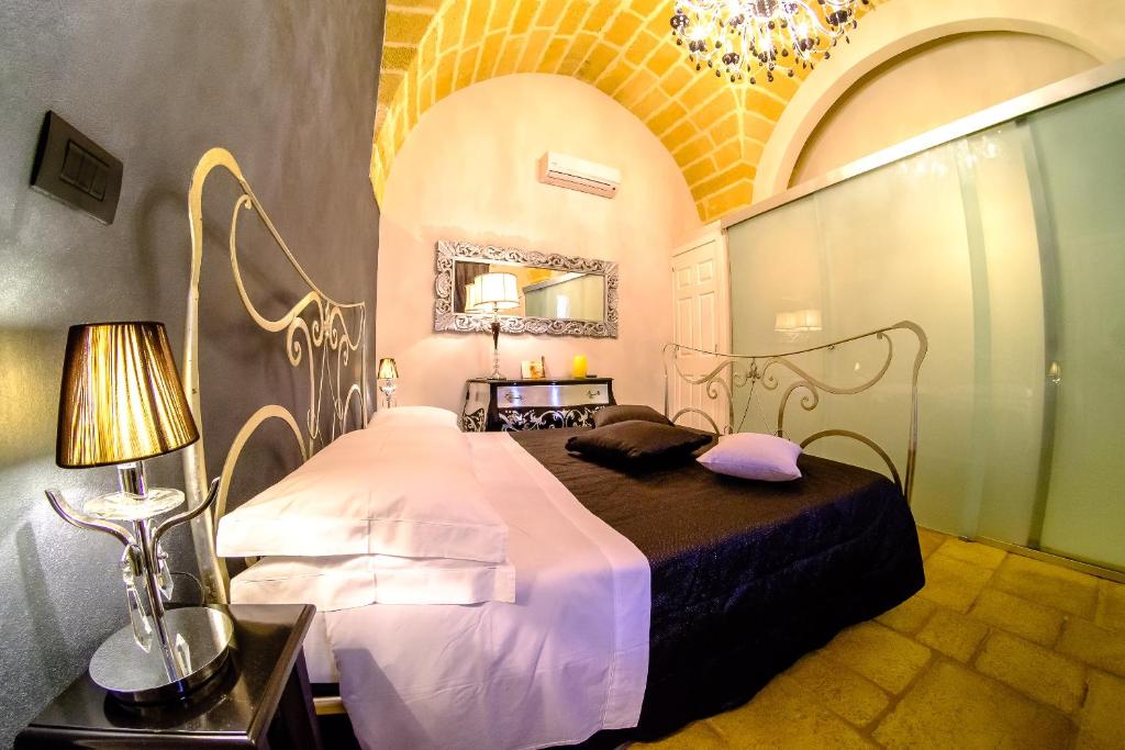 una camera con letto e lampadario a braccio di Palazzo Aurora ad Alezio