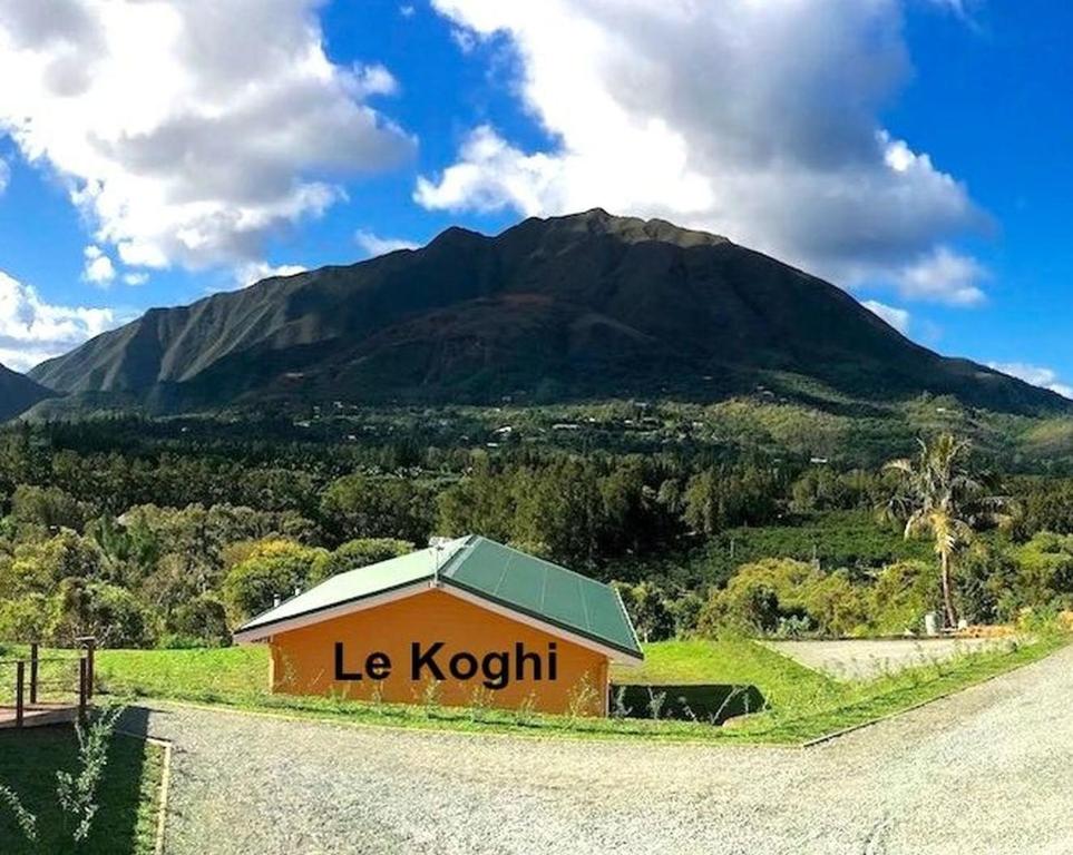 a building with the words le koticism on it next to a mountain at Gite Le Panoramique in Dumbéa