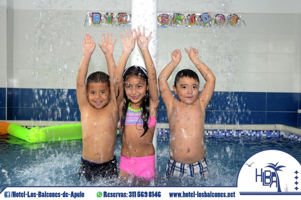 アプロにあるHotel Los Balcones de Apuloのプールに立って手を水に浸している3人の子供