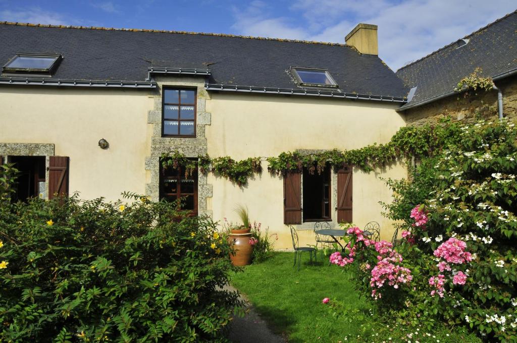 una casa gialla con un cortile fiorito di Chambre d'hotes Au Vieux Moulin a Clohars-Carnoët