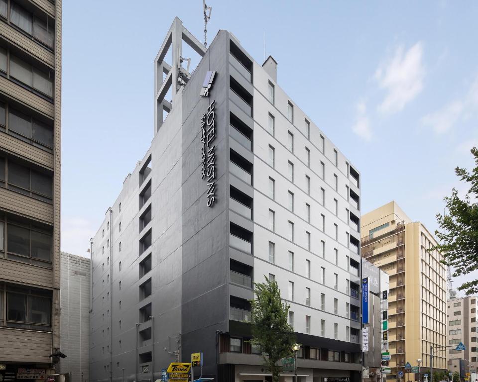 un grand bâtiment blanc avec un panneau sur celui-ci dans l'établissement Hotel Mystays Nagoya Nishiki, à Nagoya