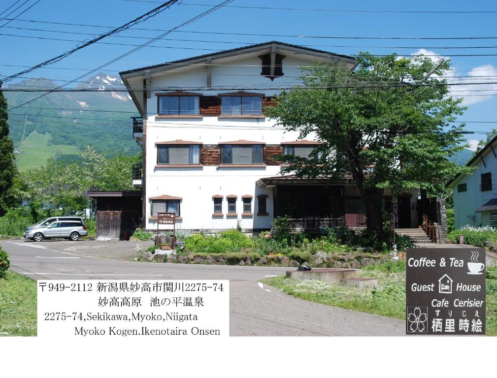 a white house with a sign in front of it at Cafe Cerisier栖里時絵 in Myoko